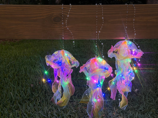 Three tie-dye jellyfish lanterns hanging and illuminated in the dark