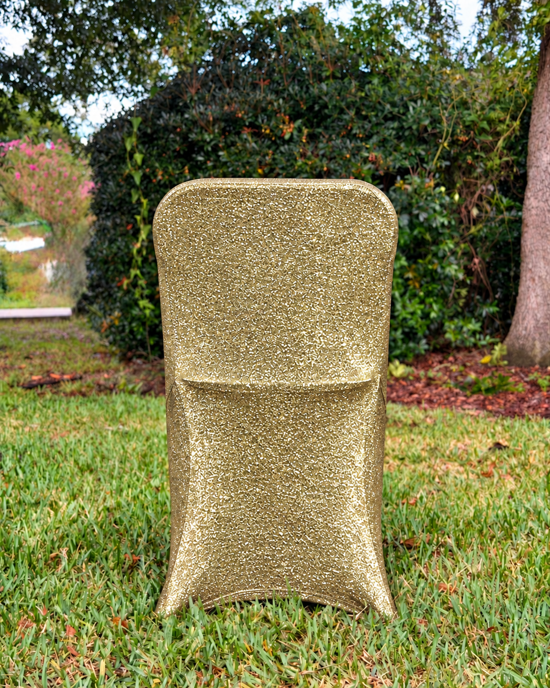 Champagne metallic shimmer chair cover shown from the back in the Cove Kits yard setting