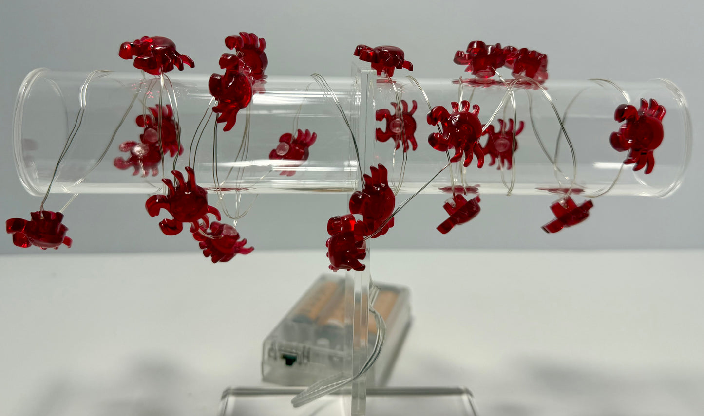 A clear acrylic spiral tube toy with multiple small red crab-shaped charms attached along the inner spiral, displayed on a clear stand against a light gray background.
