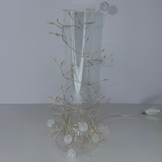 A white wall-mounted decorative light fixture with a curved backplate and branching wireframe arms holding clear globe bulbs, shown against a plain light gray wall.
