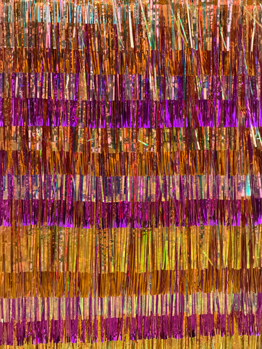 A close-up of a metallic tinsel fringe curtain with horizontal bands of gold, bronze, orange, and bright purple iridescent strands.