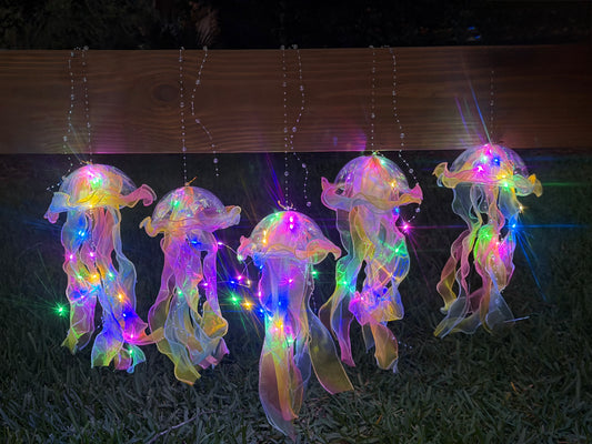 Five tie-dye jellyfish lanterns hanging and illuminated in the dark