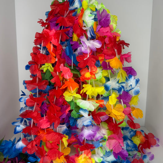 A large, vibrant hula-style flower lei made of many colorful faux hibiscus flowers, draped in a cone shape against a plain white background.