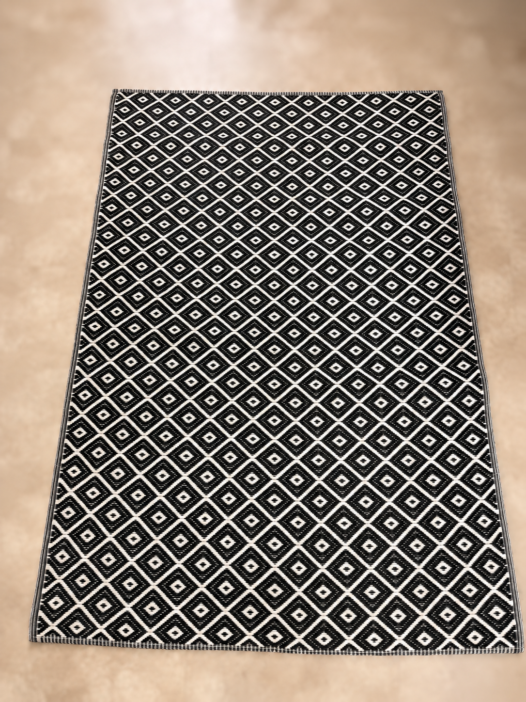 Black side of 4 by 6 foot reversible rug with white diamond pattern