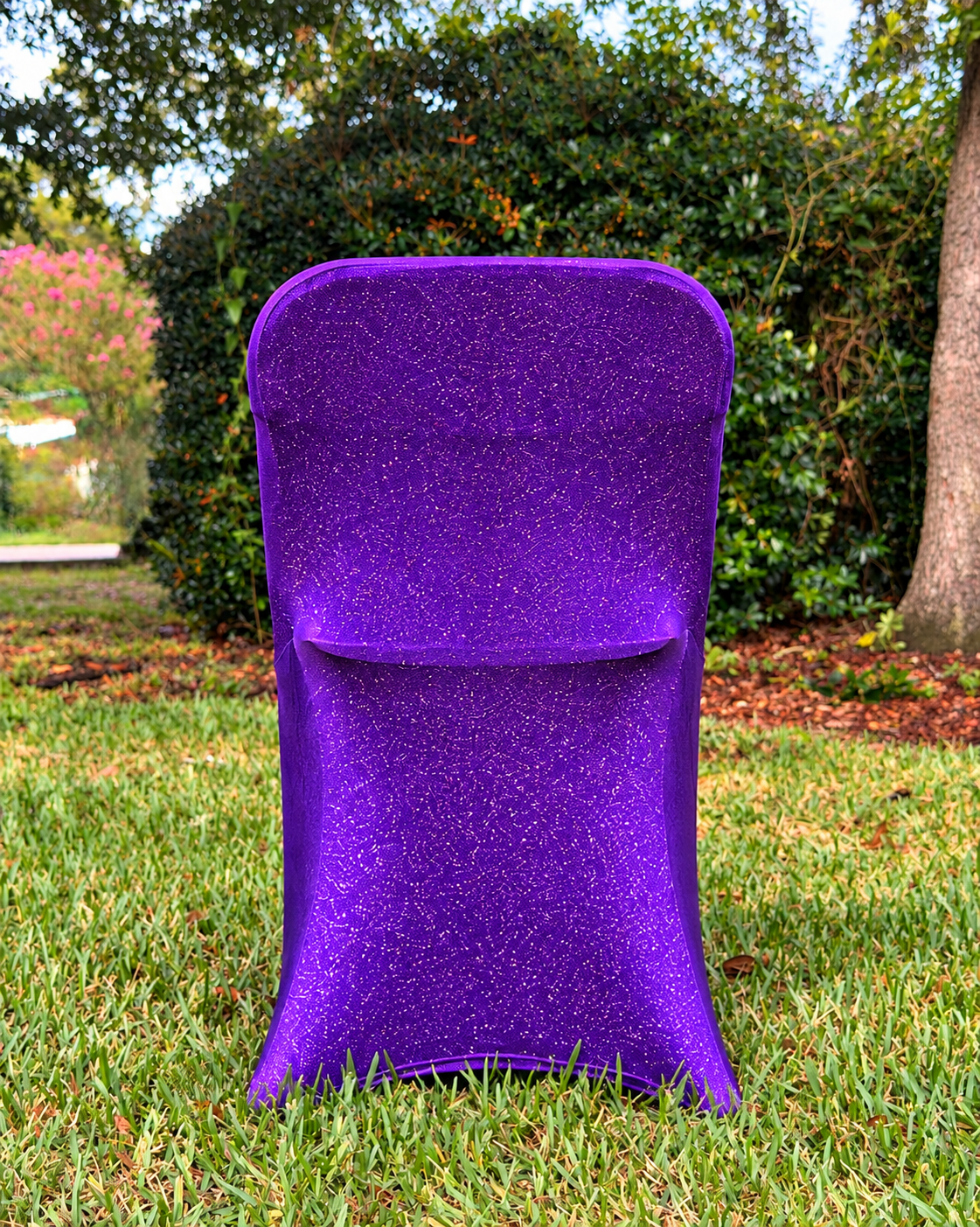 Purple metallic shimmer chair cover on a grassy lawn (styled product illustration)