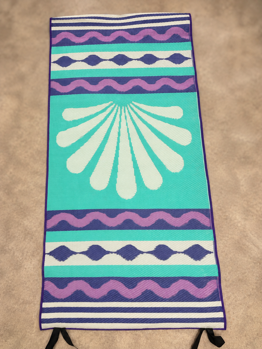 Turquoise side of reversible 76 by 36 inch rug with cream radial design and purple stripes